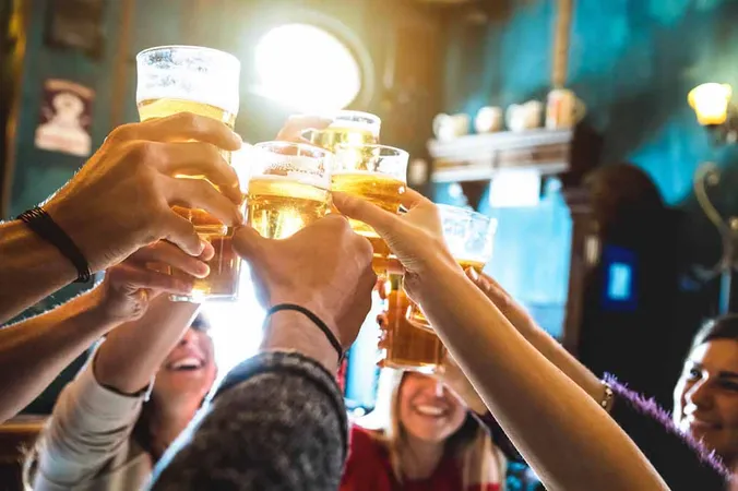 Gäste stoßen mit Bier an einem Cafétisch an.