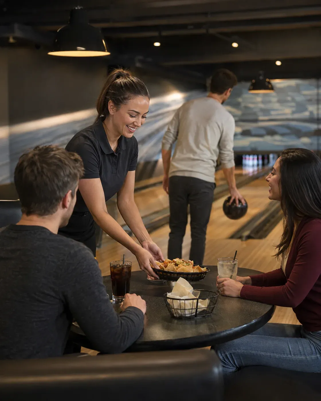 Illustrative scene of a team member bringing snacks and drinks to a group that keeps playing beside the bowling lane.
