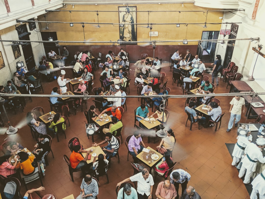 Gäste sitzen gemeinsam an langen Tischen in einem lebhaften Foodcourt.